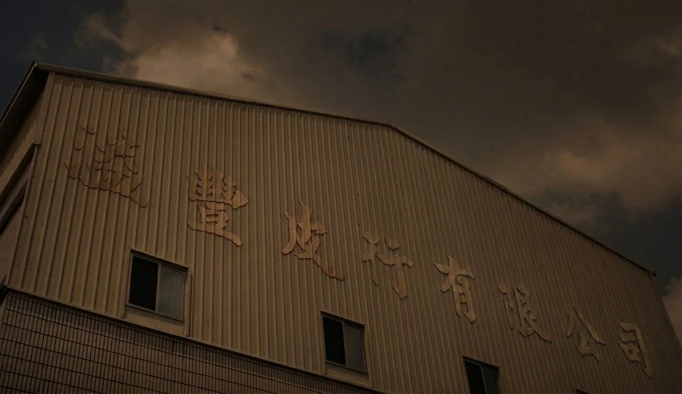 溢豐皮行有限公司的鐵皮廠房外牆與立體招牌，陰天光線